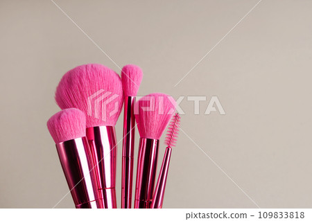 Cosmetic brushes on gray background. Set of pink makeup brushes Cosmetic brushes on gray background. Set of pink makeup brushes 109833818