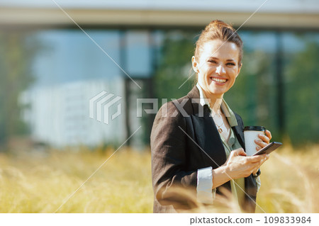 happy woman employee near office building using smartphone 109833984