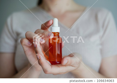 Woman holding red glass bottle with spa cosmetic oil. salon therapy, natural eco body care products Woman holding red glass bottle with spa cosmetic oil. salon therapy, natural eco body care products 109834063