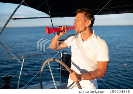 Man in a white tshirt on a yacht with a megaphone in hand 109834888