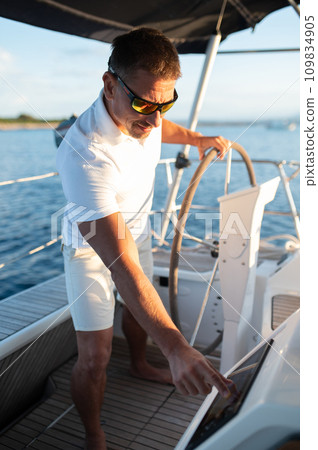 Man in white clothes sailing on a yacht Man in white clothes sailing on a yacht 109834905