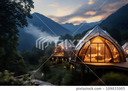 Geodesic dome cabins perched on a hillside offer a luxurious stay amidst misty mountains at dusk, with cozy interiors visible. Camping with luxury, plush bedding, and nature's beauty. Generative AI. 109835005