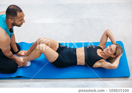 Fit woman doing sit-up with with personal trainer. 109835100