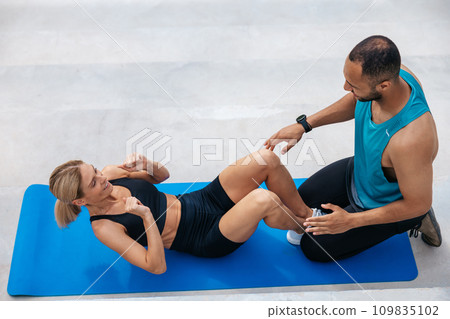 Woman with blonde hair in excellent shape doing sit-ups with her boyfriend, 109835102