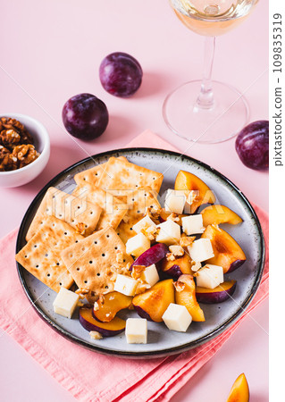 Dinner for girls, biscuits, cheese, plums and walnuts on a plate on the table vertical view Dinner for girls, biscuits, cheese, plums and walnuts on a plate on the table vertical view 109835319