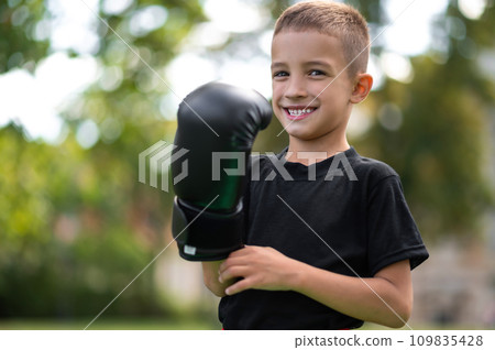Cute boy in boxing gloves looking contented and excited Cute boy in boxing gloves looking contented and excited 109835428