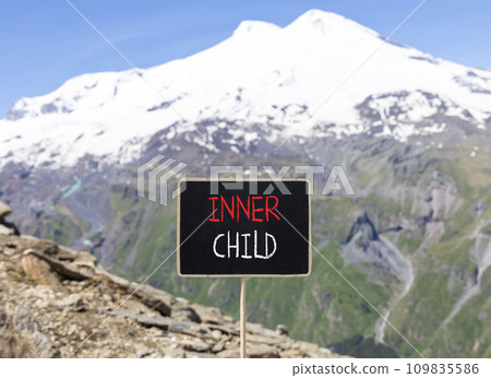Inner child symbol. Concept words Inner child on beautiful black chalk blackboard. Beautiful mountain Elbrus blue sky background. Psychological, motivational inner child concept. Copy space. 109835586