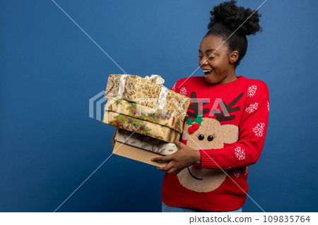 Young woman in red sweater with christmas deer holding gift boxes Young woman in red sweater with christmas deer holding gift boxes 109835764
