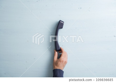 Male hand holding a black landline telephone handset Male hand holding a black landline telephone handset 109836685