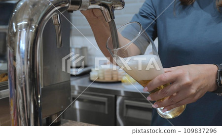 Close-up slow motion of a bartender pouring beer. The bartender pours beer into a glass. Stout, light, unfiltered beer, ready to drink. 109837296