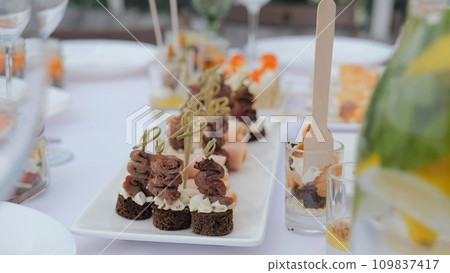 A beautiful festive table covered with a variety of food. Food and drinks on the festive table in the restaurant on birthdays, weddings. Beautifully decorated banquet table with appetizers. A beautiful festive table covered with a variety of food. Food and drinks on the festive table in the restaurant on birthdays, weddings. Beautifully decorated banquet table with appetizers. 109837417
