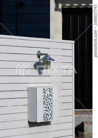 Entrance light and mailbox on white wooden fence 109837745