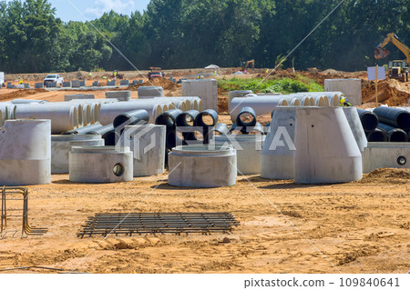 Construction site is prepared for installation of stacked concrete drainage pipes, manhole sewage pipes, storm water pipes 109840641