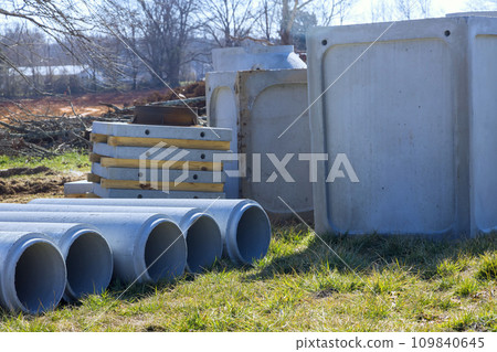 Stacks of concrete drainage pipes, manhole are awaiting installation at construction site 109840645