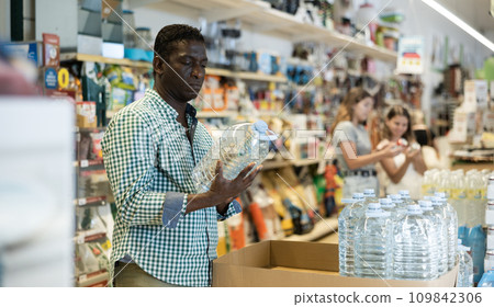Portrait of focused African American man choosing still water Portrait of focused African American man choosing still water 109842306