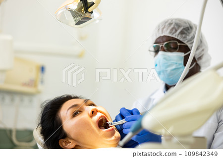 Closeup view of dentist treating teeth of woman in dentist office 109842349