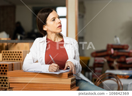 Motivated woman making notes on home space planning during renovation Motivated woman making notes on home space planning during renovation 109842369