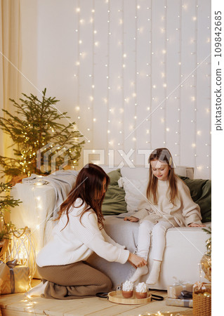Mother and daughter enjoying cozy Christmas evening. Mother and daughter enjoying cozy Christmas evening. 109842685
