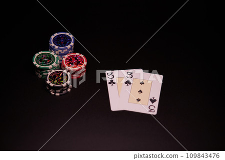 The interior of the casino. Playing cards close-up at the poker table combination of cards a pair of threes. The interior of the casino. Playing cards close-up at the poker table combination of cards a pair of threes. 109843476