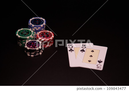 The interior of the casino. Playing cards close-up at the poker table combination of cards a pair of threes. The interior of the casino. Playing cards close-up at the poker table combination of cards a pair of threes. 109843477