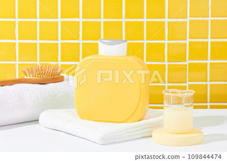 A blank yellow shower gel bottle rests on a white table against a checkered tile background. Elevate advertising with this perfect setting to showcase new shower gel. 109844474