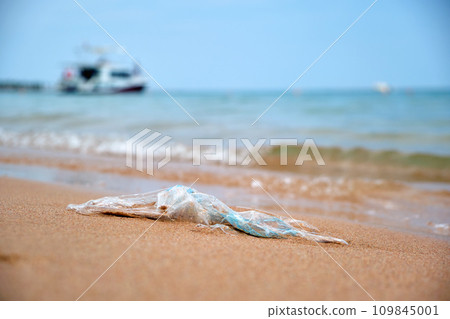 Left behind plastic bag garbage on sandy beach. Empty used dirty litter on sea shore. Environmental pollution. Ecological problem 109845001