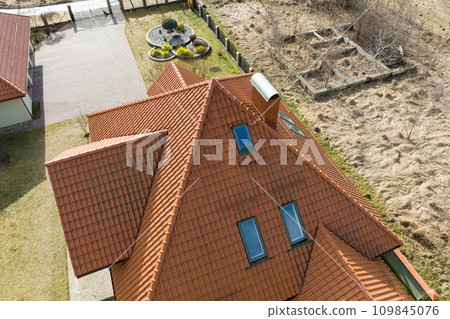 Closeup of attic windows on house roof top covered with ceramic shingles. Tiled covering of building Closeup of attic windows on house roof top covered with ceramic shingles. Tiled covering of building 109845076