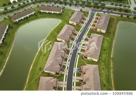 Aerial view of tightly packed homes in Florida closed living clubs with lake water in the middle. Family houses as example of real estate development in american suburbs 109845986
