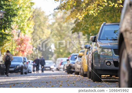 City traffic with many cars parked in line on street side 109845992