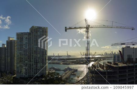 New construction site of developing residense in american urban area. Industrial tower lifting cranes in Miami, Florida. Concept of housing growth in the USA New construction site of developing residense in american urban area. Industrial tower lifting cranes in Miami, Florida. Concept of housing growth in the USA 109845997