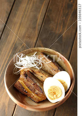 An overhead shot of thickly sliced char siu topped with white onion and boiled egg 109846317