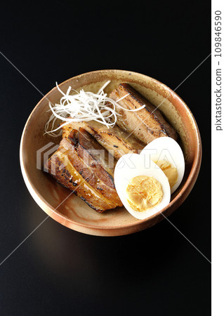 Overhead shot of thickly sliced char siu topped with white onion and boiled egg against a black background Overhead shot of thickly sliced char siu topped with white onion and boiled egg against a black background 109846590
