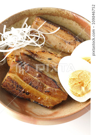 Overhead shot of thickly sliced char siu topped with white onion and boiled egg against a white background Overhead shot of thickly sliced char siu topped with white onion and boiled egg against a white background 109846752