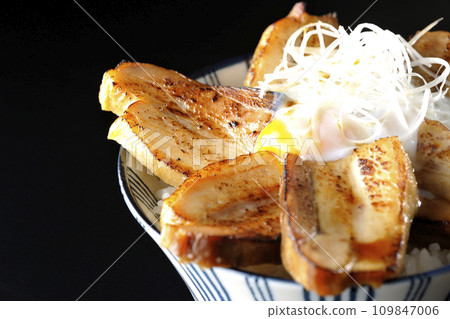 Thick-sliced char siu bowl topped with a soft-boiled egg photographed against a black background 109847006