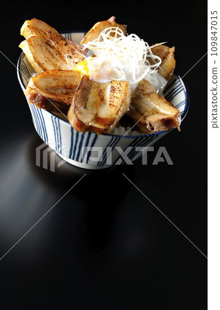 Thick-sliced char siu bowl topped with a soft-boiled egg photographed against a black background 109847015
