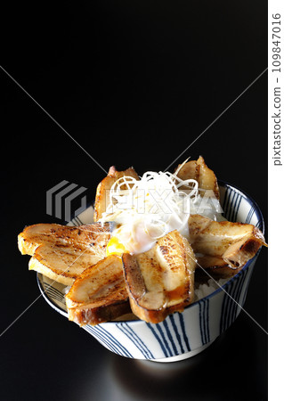 Thick-sliced char siu bowl topped with a soft-boiled egg photographed against a black background 109847016