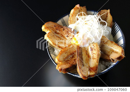 Overhead shot of thick-sliced char siu bowl topped with a soft-boiled egg against a black background Overhead shot of thick-sliced char siu bowl topped with a soft-boiled egg against a black background 109847060