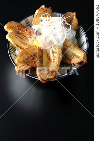 Overhead shot of thick-sliced char siu bowl topped with a soft-boiled egg against a black background 109847063