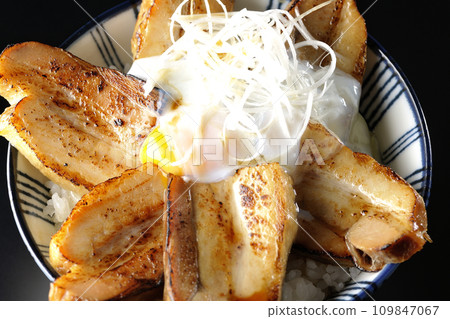 Overhead shot of thick-sliced char siu bowl topped with a soft-boiled egg against a black background 109847067