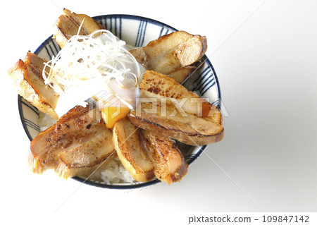 An overhead shot of a thick-sliced roasted pork bowl topped with a soft-boiled egg against a white background 109847142