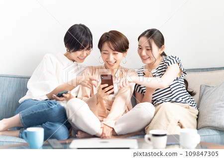 A woman relaxing on a sofa with a smartphone 109847305
