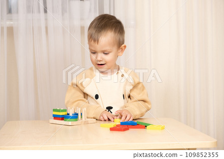 A two-year-old boy plays with wooden toys to develop logic and motor skills A two-year-old boy plays with wooden toys to develop logic and motor skills 109852355