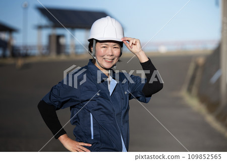 一位中年女性現場主管戴著頭盔看著鏡頭的前視圖，換崗和招募的圖像，前燈 109852565