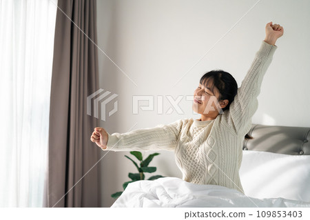 Happy Woman stretching her arms on the bed in the morning. Happy Woman stretching her arms on the bed in the morning. 109853403