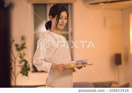 Business woman tying her hair and preparing dinner night routine Business woman tying her hair and preparing dinner night routine 109853416