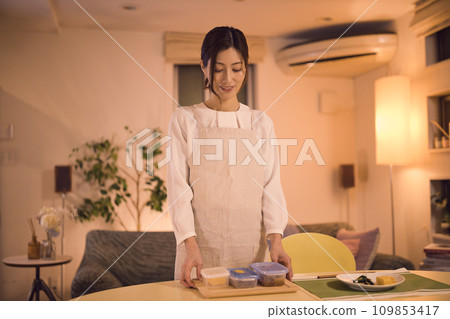 Business woman tying her hair and preparing dinner night routine 109853417