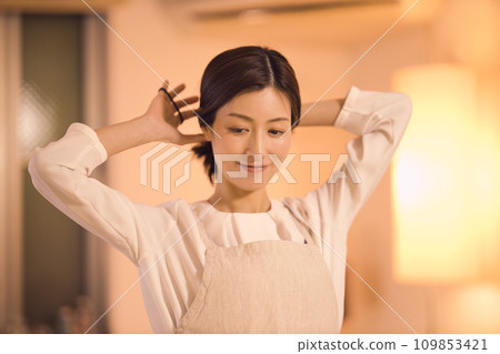 Business woman tying her hair and preparing dinner night routine 109853421