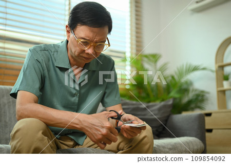 Middle age man destroying his credit card. Bankruptcy, financial problems concept. 109854092