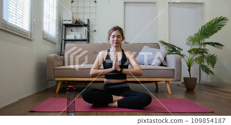 Young Asian woman meditating with trainer online at home Young Asian woman meditating with trainer online at home 109854187