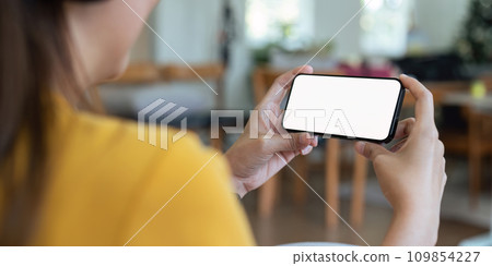 Closed up with Asian woman feels relax using smartphone in living room, Blank screen of smartphone Closed up with Asian woman feels relax using smartphone in living room, Blank screen of smartphone 109854227